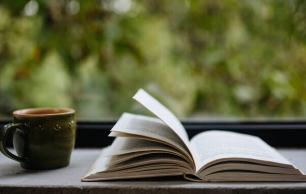 Book open with warm beverage by open window