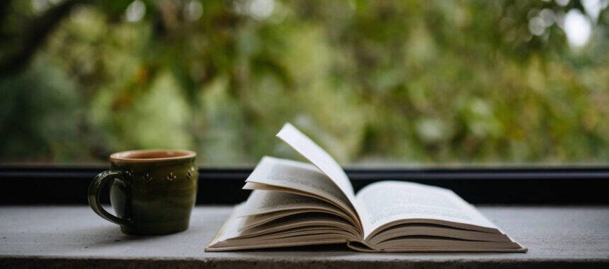 Book open with warm beverage by open window